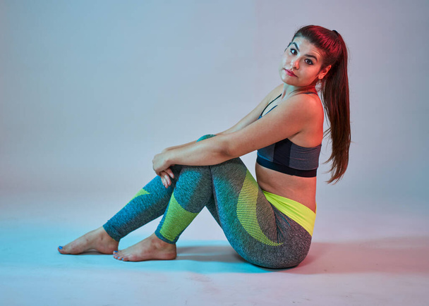 Plus size confident beautiful young woman doing fitness exercises, blue-red toning, studio shot - Foto, imagen
