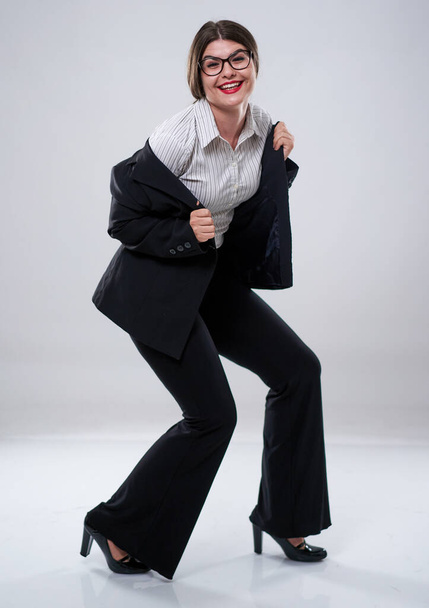 Cheerful businesswoman dancing with joy in formal suit - 写真・画像