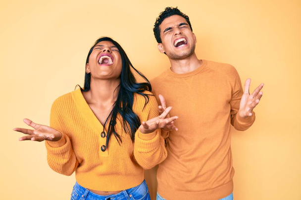 Kaunis latino nuori pari yllään rento vaatteita yhdessä juhlii hullu ja hullu menestystä kädet kohotetaan ja suljetut silmät huutaa innoissaan. voittajan käsite  - Valokuva, kuva