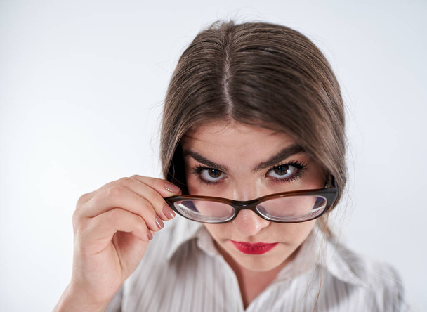 Weitwinkel-Nahaufnahme einer misstrauischen Geschäftsfrau, die über eine Brille blickt - Foto, Bild