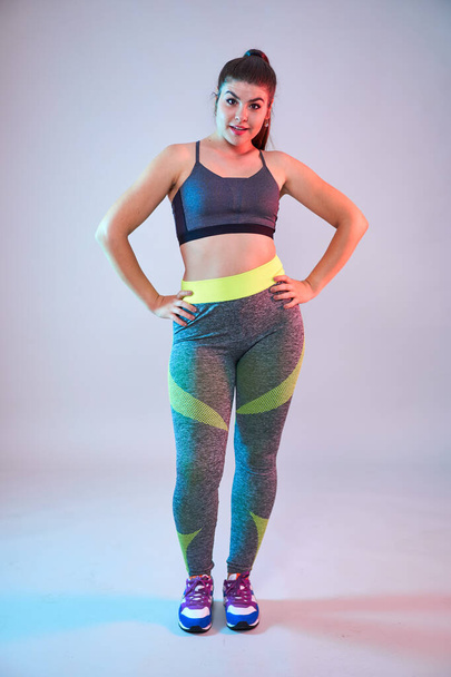 Plus size confident beautiful young woman doing fitness exercises, blue-red toning, studio shot - Foto, immagini