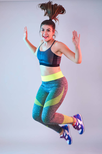 Plus size confident beautiful young woman doing fitness exercises, blue-red toning, studio shot - Zdjęcie, obraz