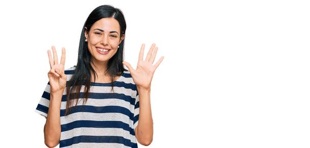 Mulher bonita vestindo roupas casuais mostrando e apontando para cima com os dedos número oito, sorrindo confiante e feliz.  - Foto, Imagem