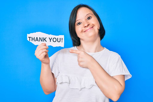 Brunette nainen alas oireyhtymä tilalla kiitos paperi hymyilee onnellinen osoittaa kädellä ja sormella  - Valokuva, kuva