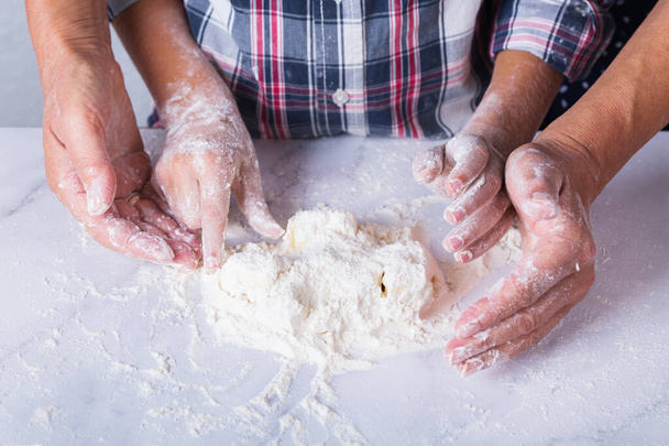 Hands of grandmother and young boy, grandson cooking, kneading dough, baking pie, cake, cookies. Family time in the cozy kitchen. Activity at home. - Foto, afbeelding
