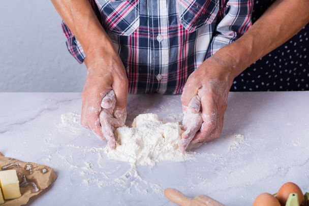 Руки бабусі та молодого хлопчика, онук готує, замішує тісто, випікає пиріг, торт, печиво. Сімейний час у затишній кухні. Діяльність вдома
. - Фото, зображення