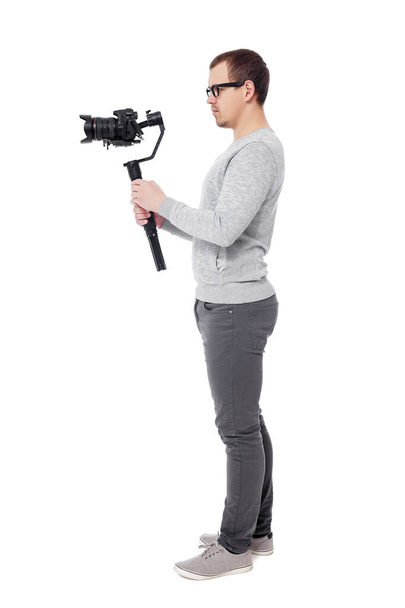 Beyaz arkaplanda izole edilmiş titreşim dengeleyicisi üzerinde dslr kamera kullanan profesyonel videografın tam uzunluk kenar görünümü - Fotoğraf, Görsel