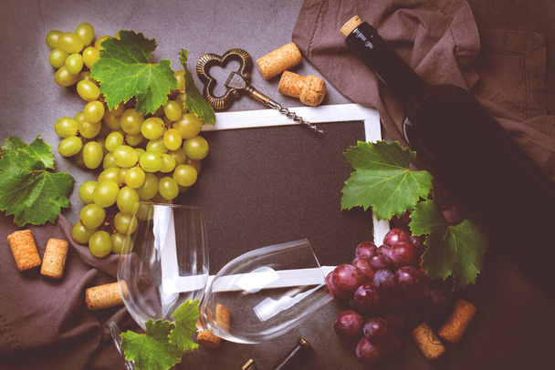 Eten en drinken, herfst herfst concept. Wijnproeverij, degustation, uitnodigingskaart met symbolen - wijnstok, fles, glazen, kurkentrekker. Zwarte achtergrond, afgezwakt - Foto, afbeelding