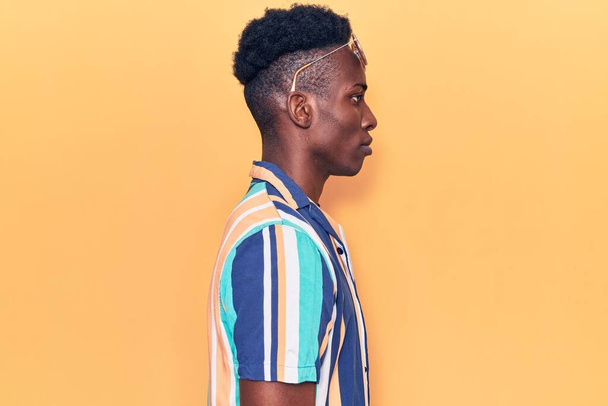 Young african american man wearing summer clothes and sunglasses looking to side, relax profile pose with natural face with confident smile.  - Valokuva, kuva
