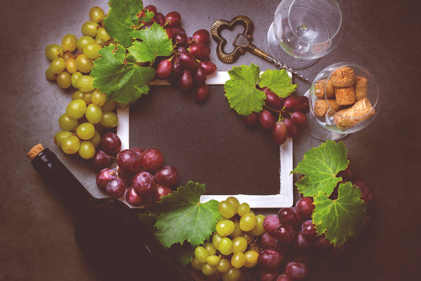 Comida e bebida, colheita outono outono conceito de queda. Degustação de vinhos, degustação, cartão de convite com símbolos - videira de uva, garrafa, copos, saca-rolhas. Fundo preto, tonificado - Foto, Imagem