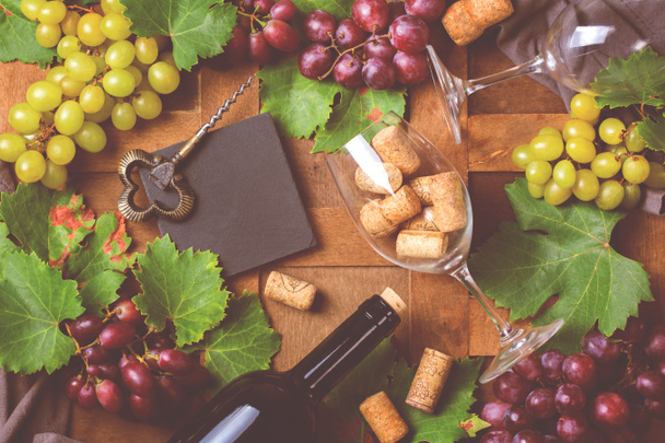 Eten en drinken, herfst herfst concept. Wijnproeverij, degustation, uitnodigingskaart met symbolen - wijnstok, fles, glazen, kurkentrekker. Houten achtergrond, afgezwakt - Foto, afbeelding