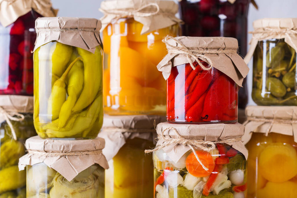 Preserved and fermented food. Assortment of homemade jars with variety of pickled and marinated vegetables, fruit compote on a wooden table. Housekeeping, home economics, harvest preservation   - Фото, зображення