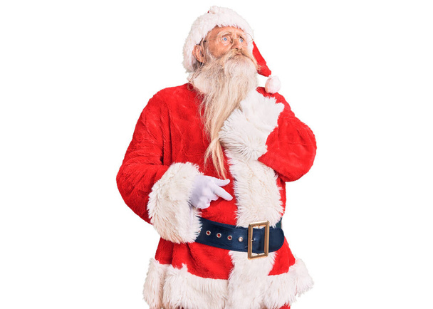 Oude senior man met grijs haar en lange baard draagt traditionele kerstman kostuum aanraken pijnlijke nek, keelpijn voor griep, clod en infectie  - Foto, afbeelding
