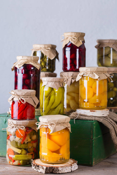 Preserved and fermented food. Assortment of homemade jars with variety of pickled and marinated vegetables, fruit compote on a wooden table. Housekeeping, home economics, harvest preservation   - Photo, Image