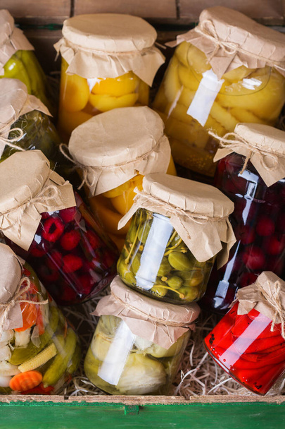 Preserved and fermented food. Assortment of homemade jars with variety of pickled and marinated vegetables, fruit compote on a wooden table. Housekeeping, home economics, harvest preservation   - Photo, Image