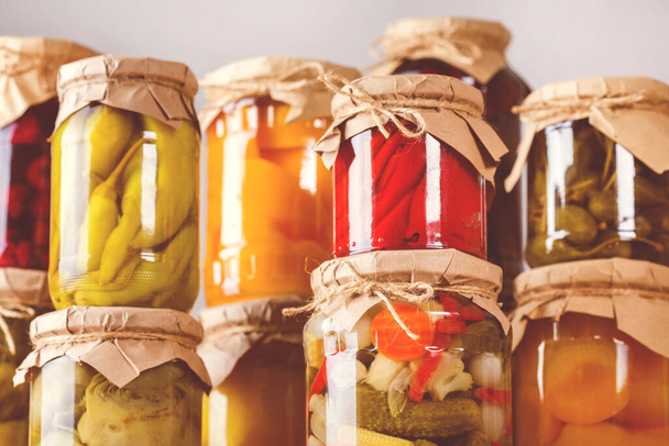 Preserved and fermented food. Assortment of homemade jars with variety of pickled and marinated vegetables, fruit compote on a wooden table. Housekeeping, home economics, harvest preservation. Toned - Foto, afbeelding