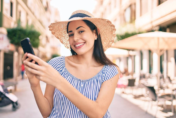 Young latin tourist girl on vacation smiling happy  using smartphone at the city. - Foto, Bild