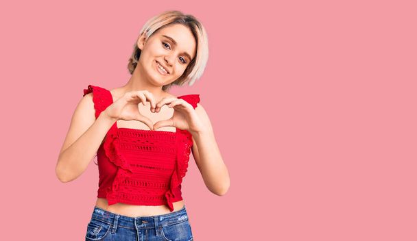 Young beautiful blonde woman wearing casual clothes smiling in love doing heart symbol shape with hands. romantic concept.  - Photo, Image