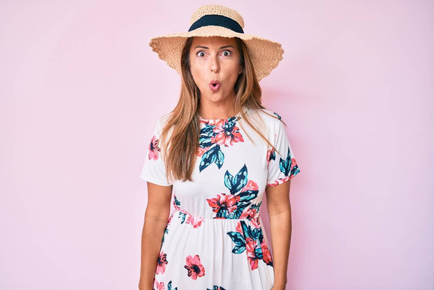 Middle age hispanic woman wearing summer hat scared and amazed with open mouth for surprise, disbelief face  - Photo, Image