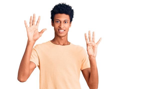 Mladý africký Američan nosí ležérní oblečení ukazující a ukazující nahoru s prsty číslo devět a zároveň se usmívá sebevědomě a šťastně.  - Fotografie, Obrázek