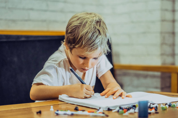 Portrait blond cute Preschool boy holding pen notebook look serious hard diligently diligently learn write, facial expressions gestures. Children behaviour education problems, home school concept - Photo, Image