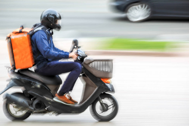 masked business people in a city delivery on the bike in traffic on the city roadway on a rainy day motion blur - Fotoğraf, Görsel