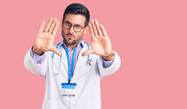 Nuori latino mies yllään lääkäri yhtenäinen ja stetoskooppi tekee runko käyttäen käsien kämmenet ja sormet, kameran näkökulmasta  - Valokuva, kuva