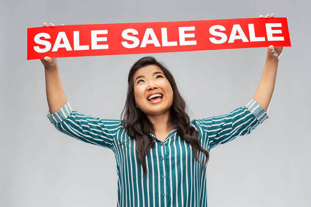 happy smiling young asian woman with sale banner - Фото, зображення