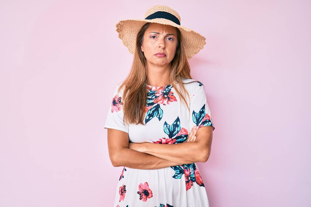 Femme hispanique du Moyen Âge portant un chapeau d'été sceptique et nerveux, désapprouvant l'expression sur le visage avec les bras croisés. personne négative.  - Photo, image
