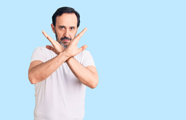Middle age handsome man wearing casual t-shirt rejection expression crossing arms doing negative sign, angry face  - Photo, Image