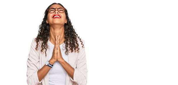 Jeune fille afro-américaine portant des vêtements de travail mendier et prier avec les mains ainsi que l'expression de l'espoir sur le visage très émotionnel et inquiet. mendier.  - Photo, image