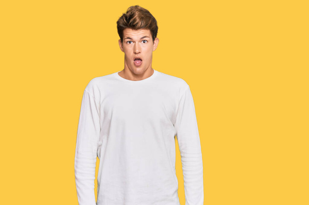 Handsome caucasian man wearing casual white sweater afraid and shocked with surprise and amazed expression, fear and excited face.  - Photo, Image