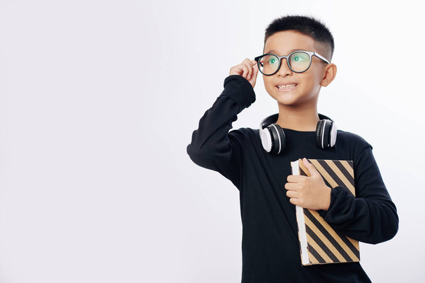 Inteligentny utalentowany wietnamski dzieciak w okularach korekcyjnych i odwracając wzrok - Zdjęcie, obraz