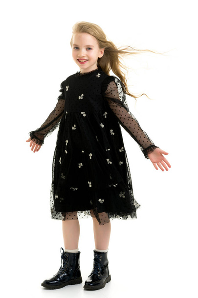 A beautiful little girl stands in the wind, her hair and clothes. - Foto, Imagen