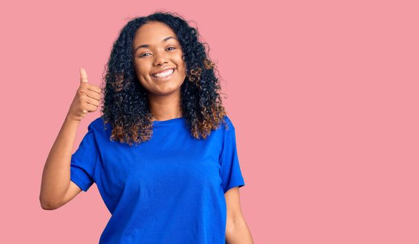 Young african american woman wearing casual clothes smiling happy and positive, thumb up doing excellent and approval sign  - Фото, зображення