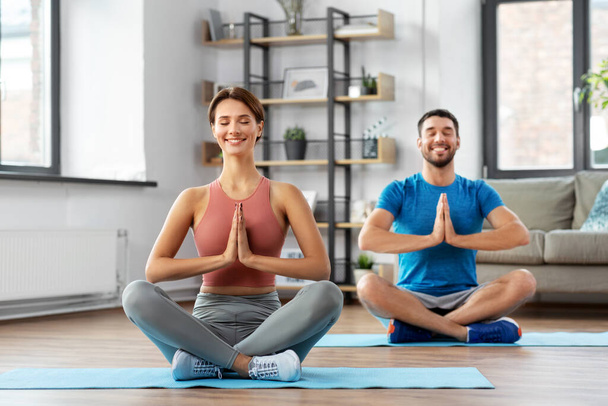 glückliches Paar meditiert zu Hause in Yoga-Lotus-Pose - Foto, Bild