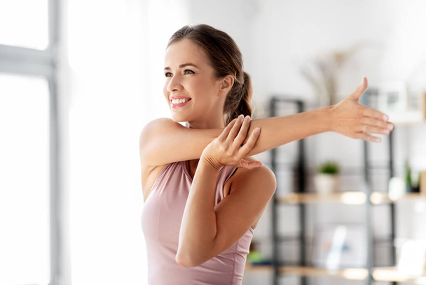 smiling young woman stretching arm at home - Fotoğraf, Görsel