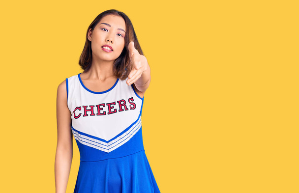 Junge schöne chinesische Mädchen tragen Cheerleader-Uniform lächelnd fröhlich bietet Palm Hand geben Hilfe und Akzeptanz.  - Foto, Bild