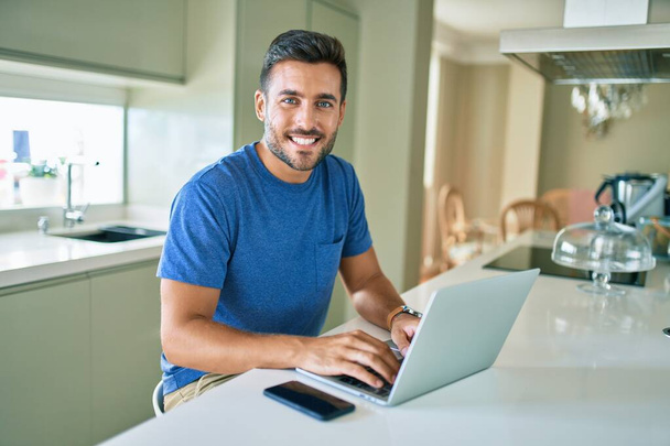 Young handsome man smiling happy working using laptop at home - Фото, зображення