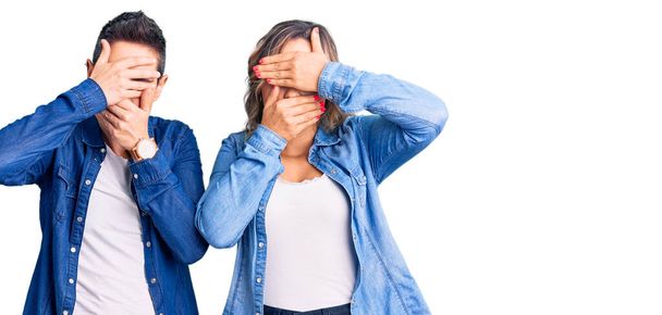Couple of women wearing casual clothes covering eyes and mouth with hands, surprised and shocked. hiding emotion  - Photo, Image