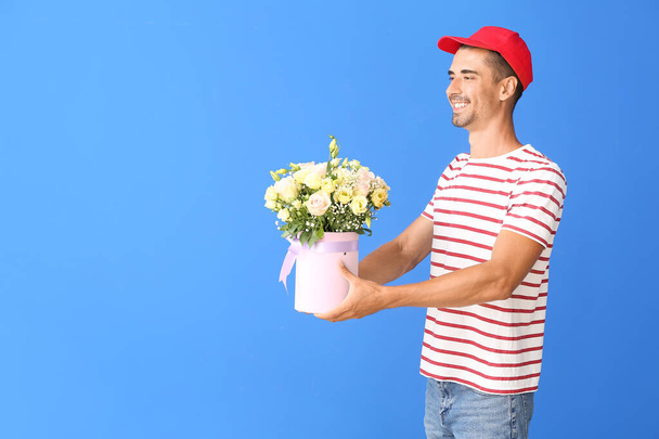 Delivery man with bouquet of flowers on color background - Photo, Image