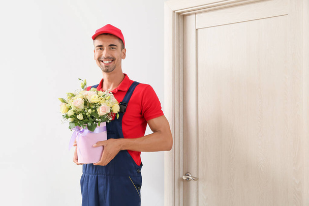 Livraison homme avec bouquet de fleurs près de la porte du client - Photo, image