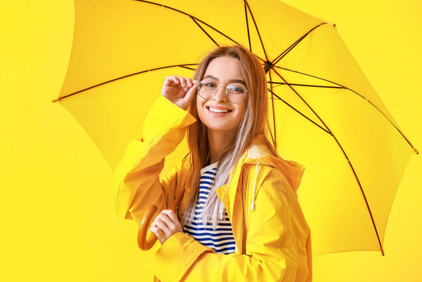 Kaunis nuori nainen sadetakki ja sateenvarjo väri tausta - Valokuva, kuva