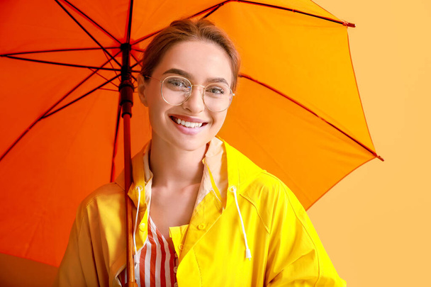 Красива молода жінка в плащі і з парасолькою на кольоровому фоні
 - Фото, зображення