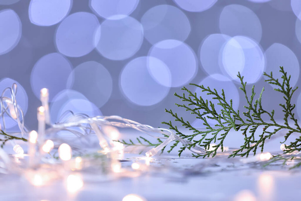 Kozalaklı ağaç dalı ve Noel ışıkları masanın üstünde. - Fotoğraf, Görsel