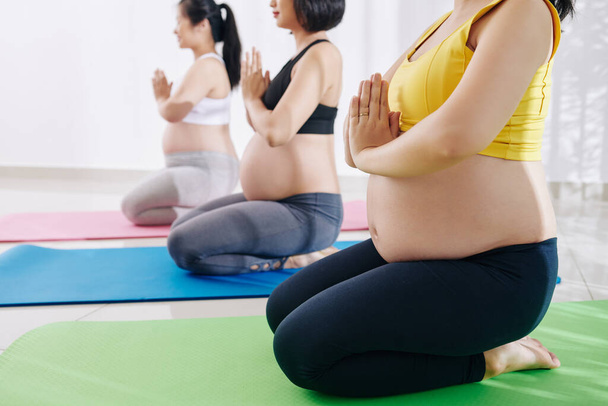 Группа беременных молодых женщин, практикующих йогу в учебном классе - Фото, изображение
