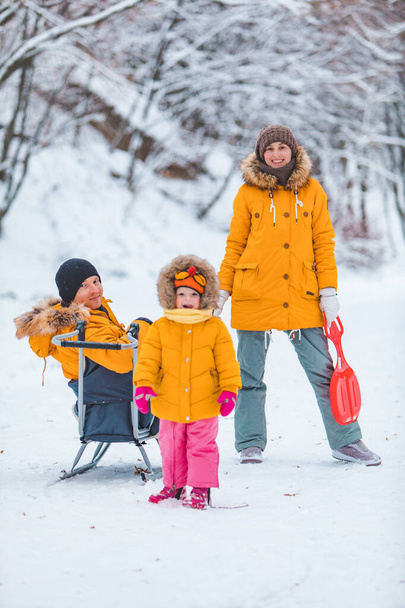 молодая семья собирается вместе на открытом воздухе в снежный зимний день желтые пальто семья выглядит - Фото, изображение