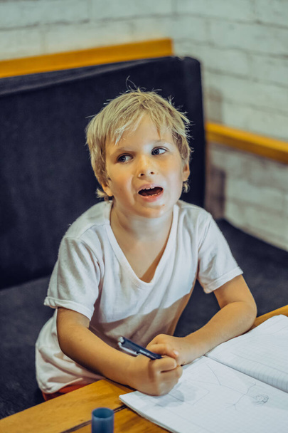 Preschool boy mischievous dreamy intriguing funny look, open mouth, thoughtful hold pen notebook, think idea draw doodle, facial expressions gestures. Home education, develop imagination concept - Foto, Bild