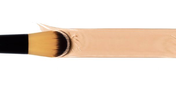 Cosmetology Art Konzeptbanner mit Make-up-Pinsel in Nahaufnahme, das flüssige Fundament auf weißem Untergrund aufträgt. Beauty, Hautpflege und Make-up Hautperfektionskonzept - Foto, Bild