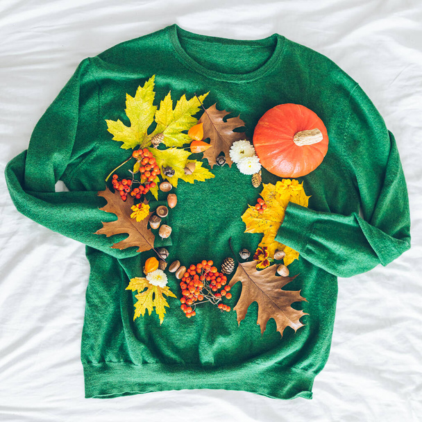 πράσινο πουλόβερ με φθινοπωρινά κίτρινα φύλλα και πορτοκαλί κολοκύθα. ευχετήρια κάρτα. αντίγραφο χώρου - Φωτογραφία, εικόνα